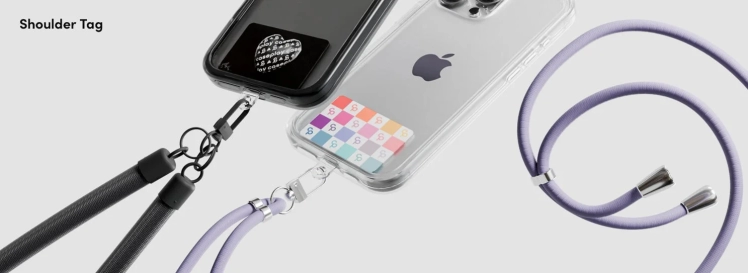 スマートフォンケースにショルダーストラップを取り付けている様子を捉えた画像です。クリアケースと黒いケースの2種類があり、それぞれ異なる色のストラップが装着されています。ハンズフリーでスマートフォンを持ち運ぶためのアクセサリーを紹介しています。