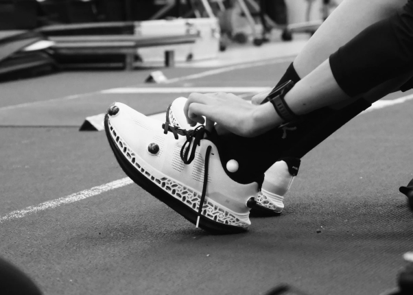 ランニングシューズの靴ひもを結ぶアスリートのモノクロ画像