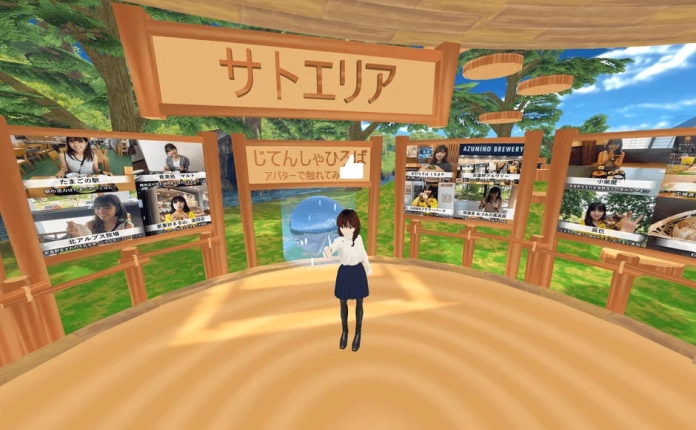 仮想空間「サトエリア」の広場に立つアバターの女性。周囲には安曇野地域の観光地や特産品を紹介するデジタルサイネージが並び、情報発信の場となっている様子が描かれている。