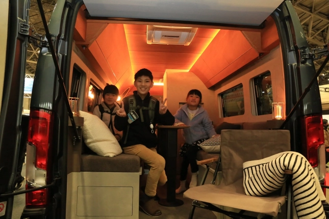 キャンピングカーの車内で子供たちが笑顔でポーズ