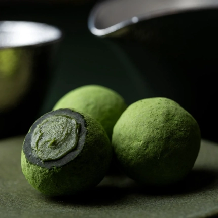 暗い背景に置かれた3つの抹茶トリュフ