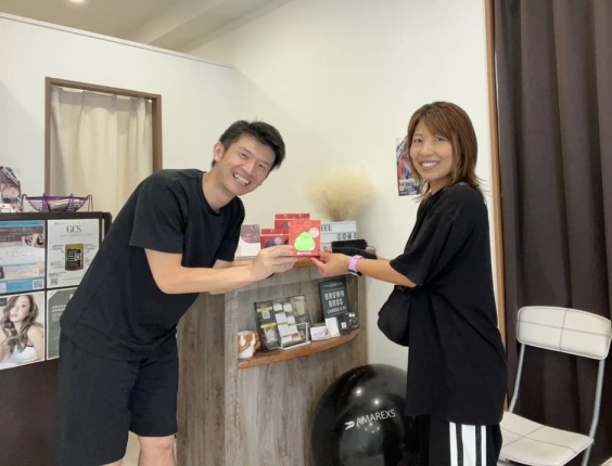 男性と女性が笑顔で緑色の小さな商品を手にしている写真。