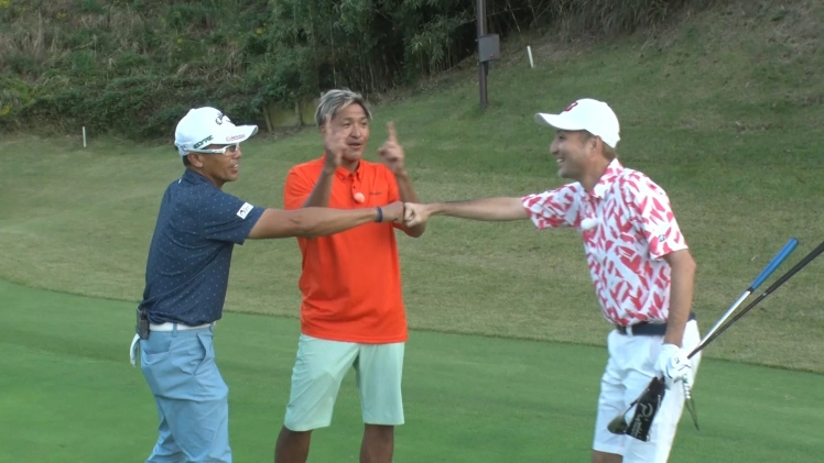 ゴルフ場で3人の男性が楽しそうに交流しています