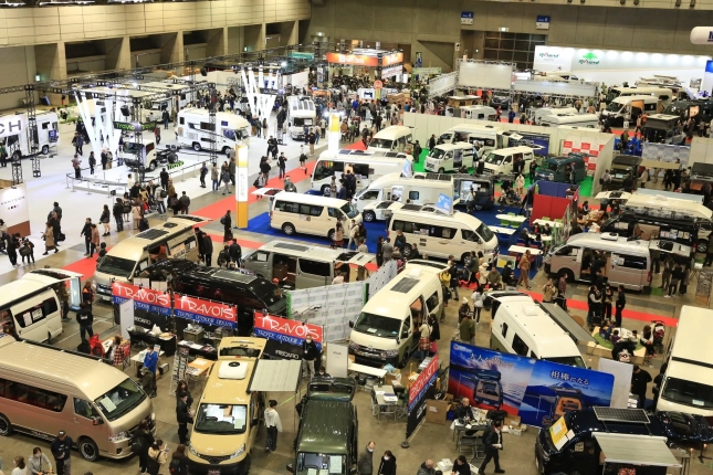 多数のキャンピングカーやバンが展示された屋内イベント会場
