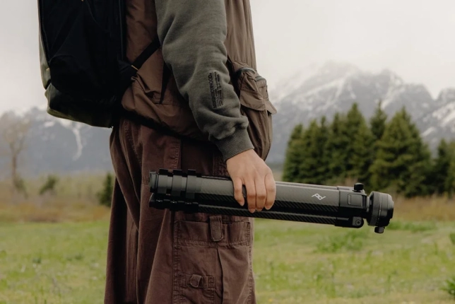 雪山を背景に三脚を持つ男性